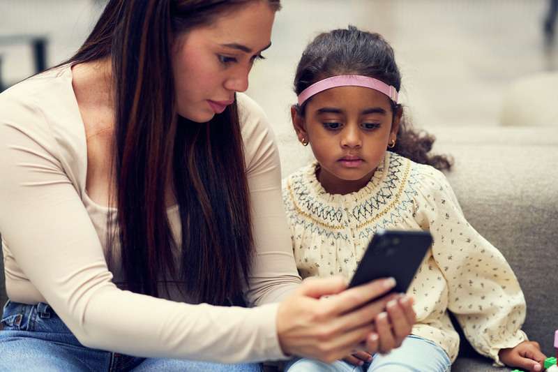 Un jeune porteur de Baha Start et sa mère regardant ensemble un téléphone.