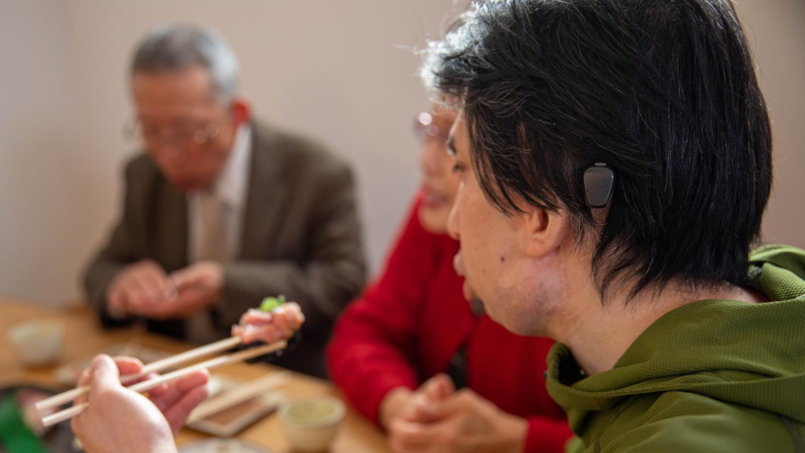 Cochlear recipient talks to a friend at a cafe