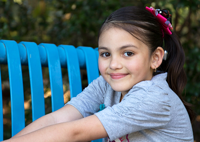 Cochlear™ implantátumot viselő fiatal lány mosolyog a kamerába