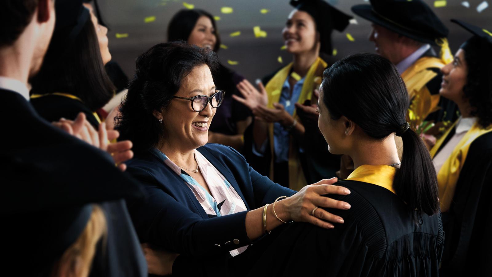 Una mujer le sonríe a su hija durante una ceremonia de graduación