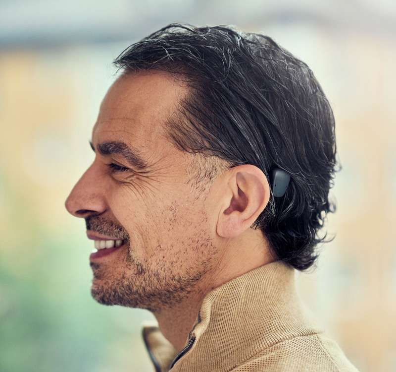 Homme portant un processeur Baha 7 noir. Il est de profil pour montrer le processeur derrière son oreille.