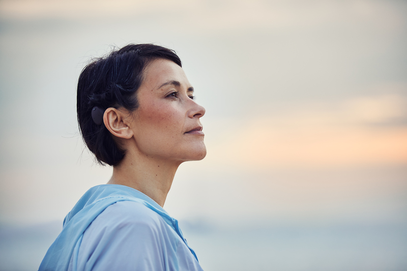 Tête de femme caucasienne regardant au loin et portant un implant Osia