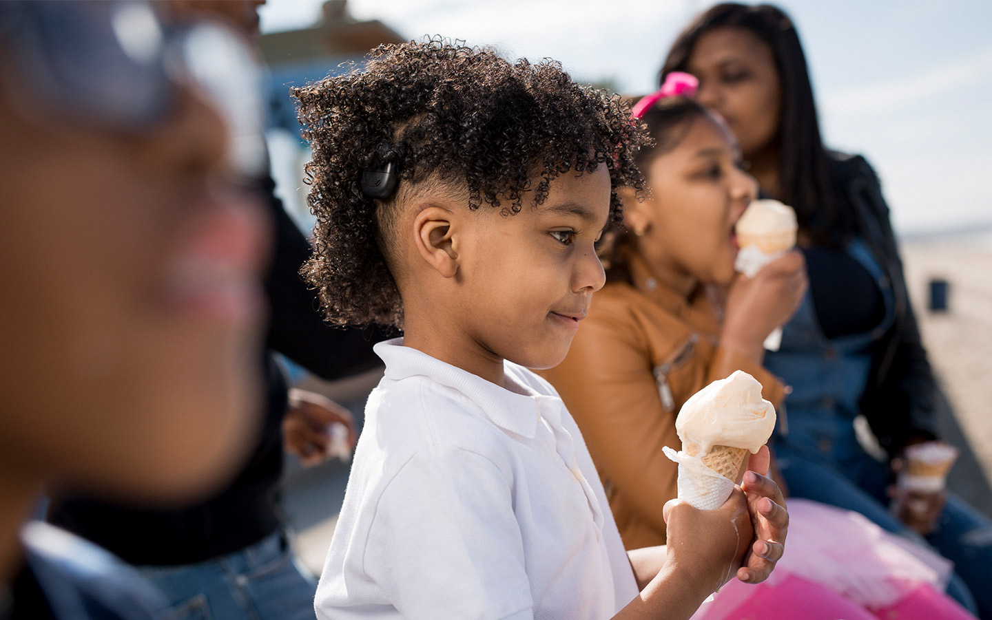 Young boy eats ice cream with his friends while wearing Nucleus device