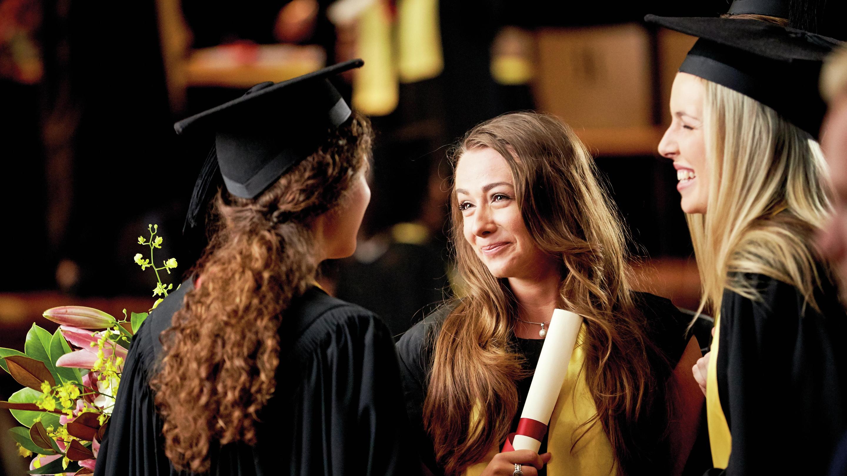 Drie vrienden praten na het behalen van hun diploma van de universiteit