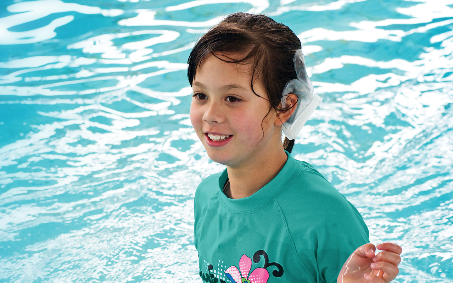 A girl wears her Nucleus water-safe accessory as she plays in the pool