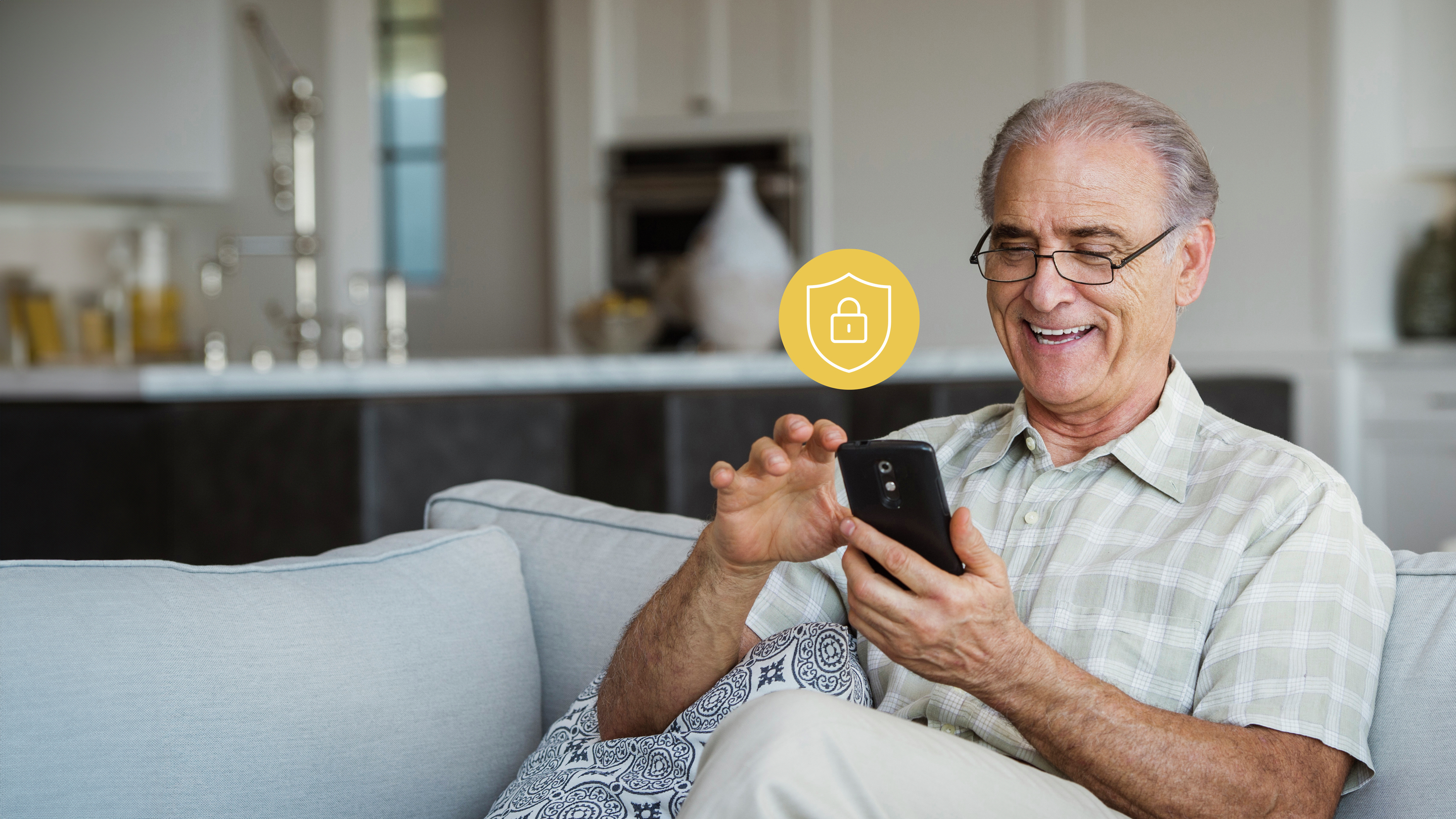 An older man smiling, viewing information on his smartphone. A security icon indicates his information is safe. 