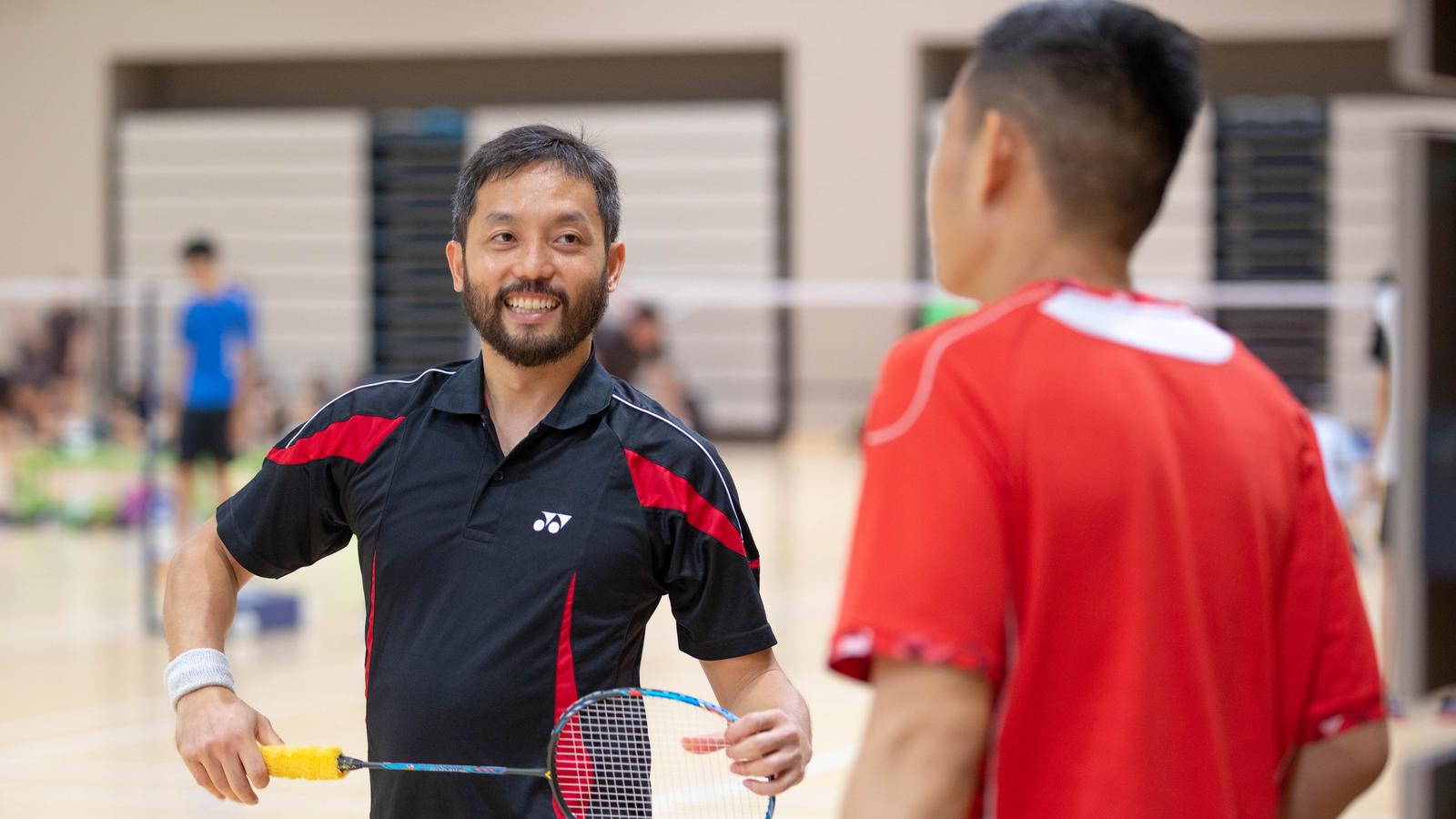 A man smiles as he plays shuttlecock