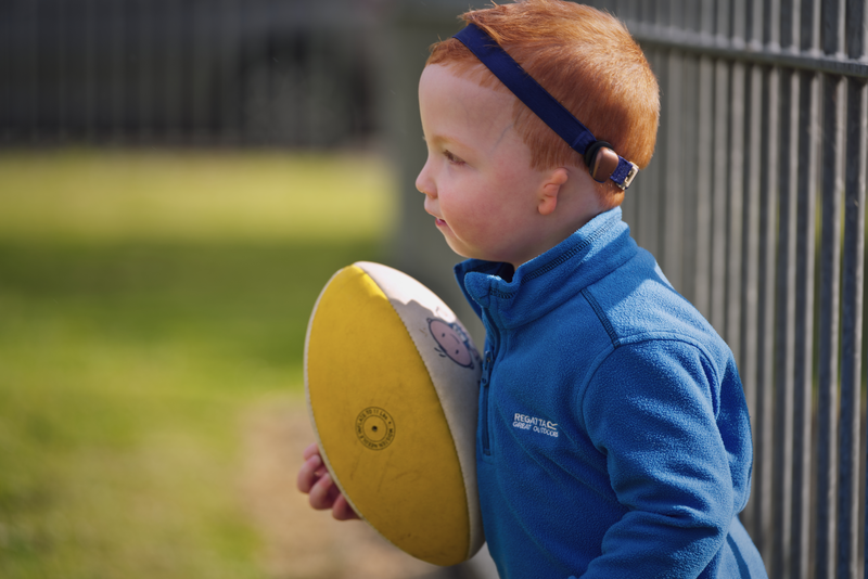 A boy playing ball while wearing a Cochlear Baha SoundBand.