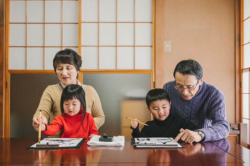 書道を行っているアジア人の多世代家族