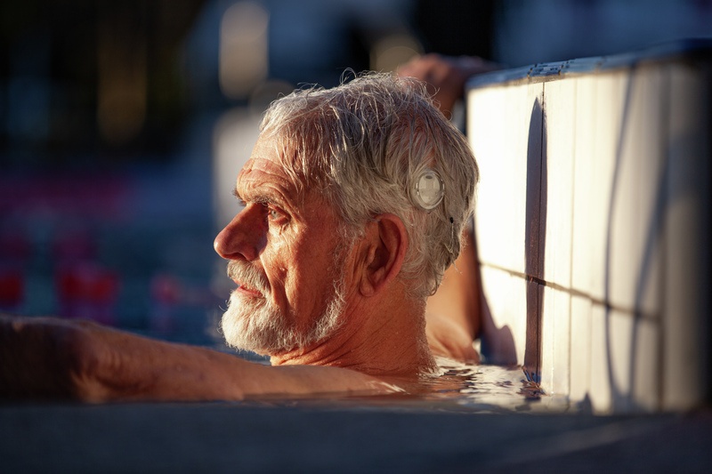 Man in pool with Cochlear water-safe accessory protecting his sound processor.