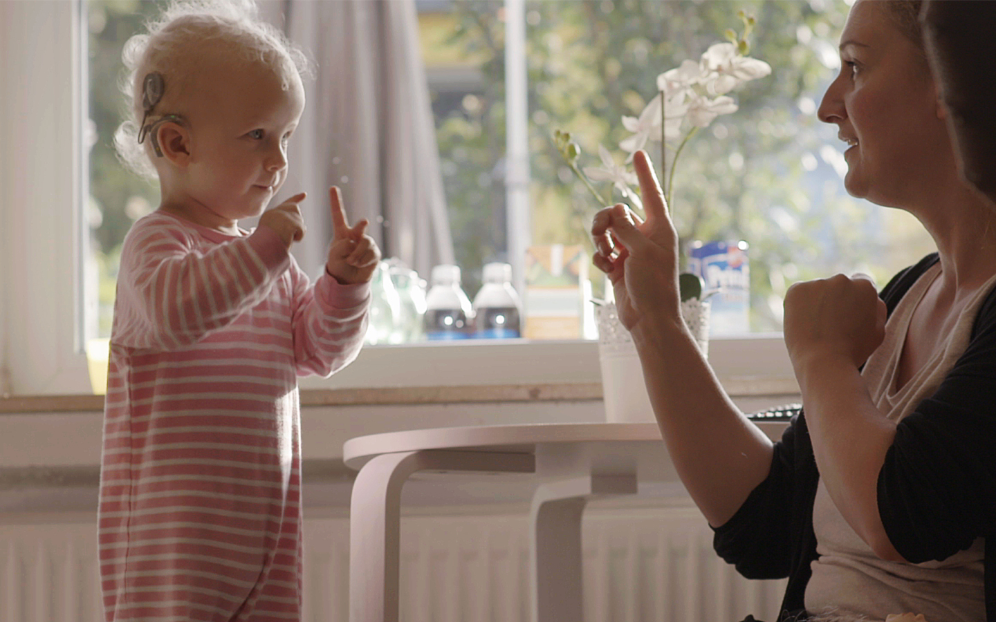 A woman interacts with a toddler wearing a Cochlear implant