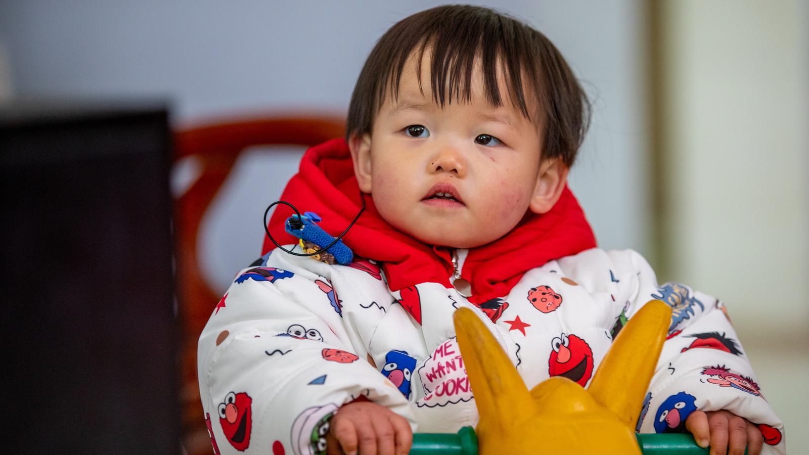 A woman interacts with a toddler wearing a Cochlear implant