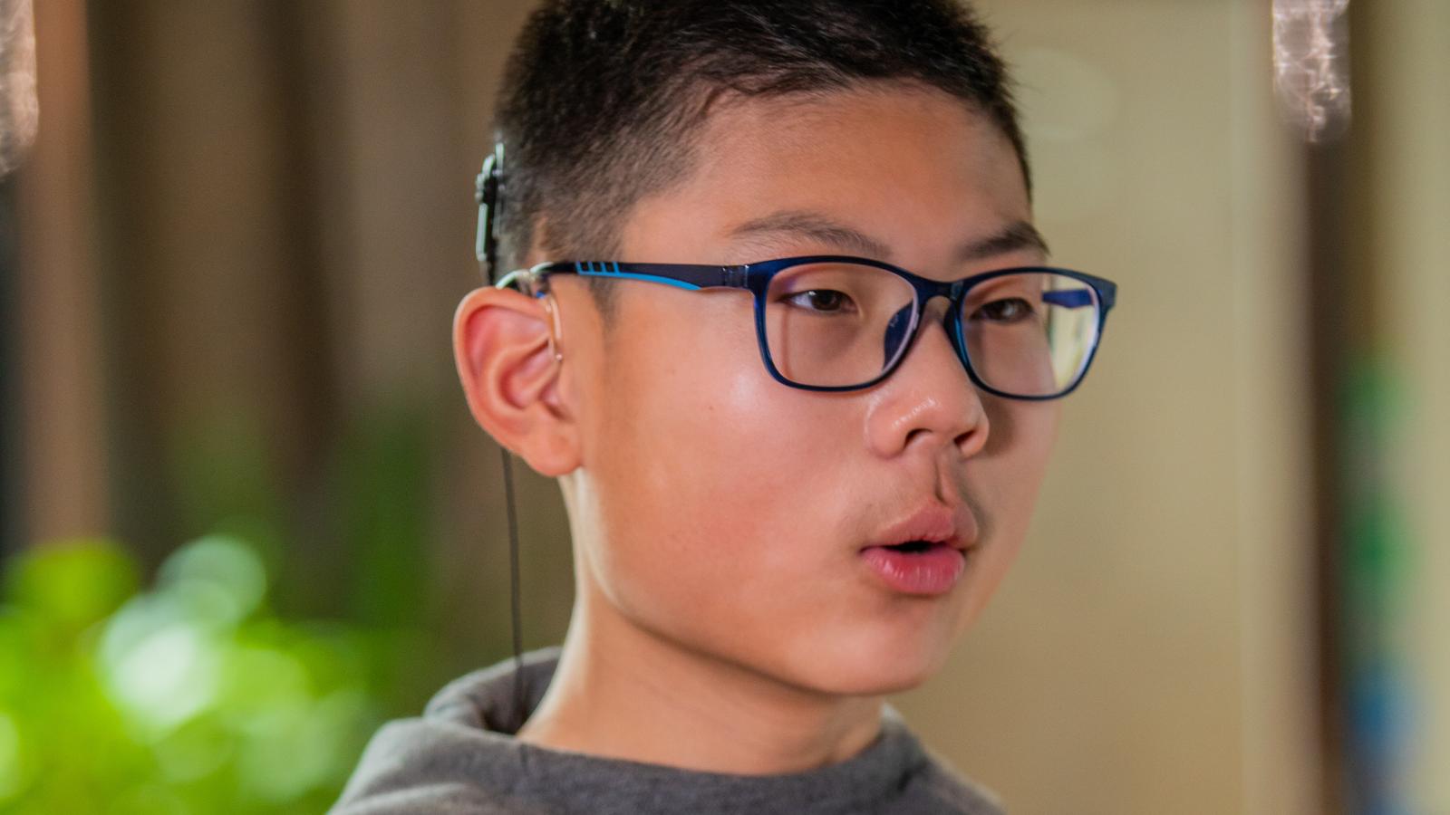 Một bé trai đeo thiết bị cấy ghép đang luyện tập trị liệu ngôn ngữ
