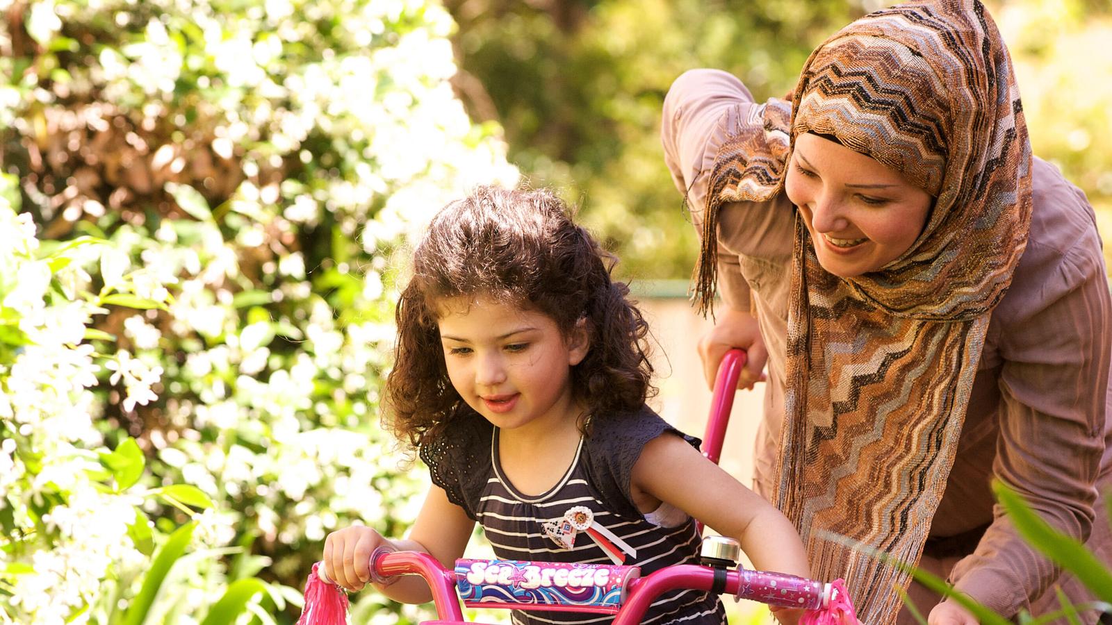 Egy édesanya a lányát tanítja kerékpározni