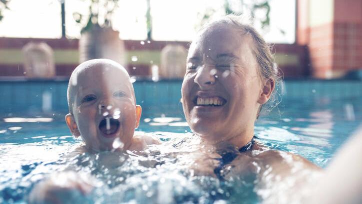 Une femme et un bébé s’éclaboussent dans une piscine
