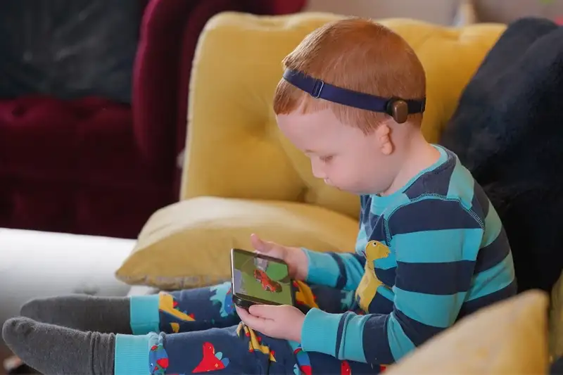 Jeune porteur d’un Baha Start regardant une vidéo sur un téléphone. Le son est directement diffusé depuis votre téléphone vers le processeur.