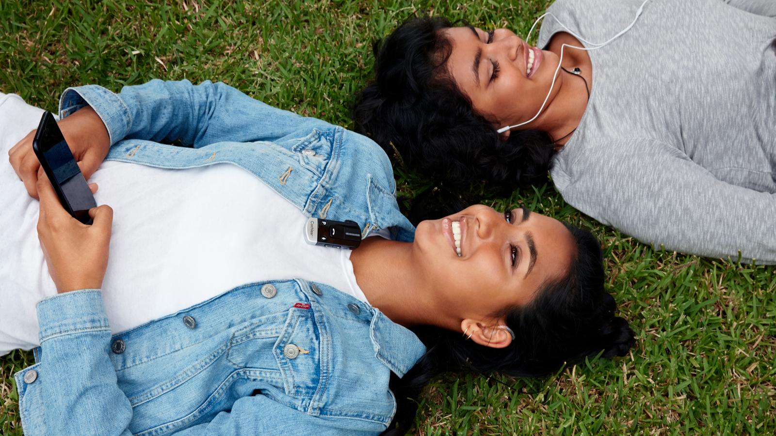 Des amis allongés sur l’herbe parlent avec un mini-microphone