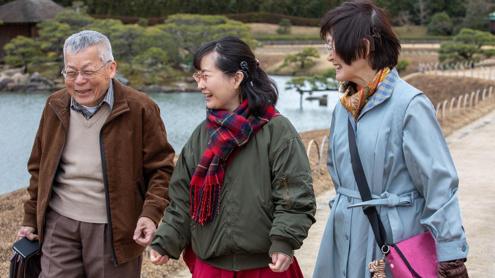 A man wearing a Cochlear implant talks to a friend on a golf course