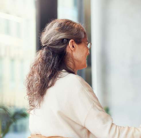 Femme portant un processeur Baha 7. Elle est de profil pour montrer le processeur noir derrière son oreille.