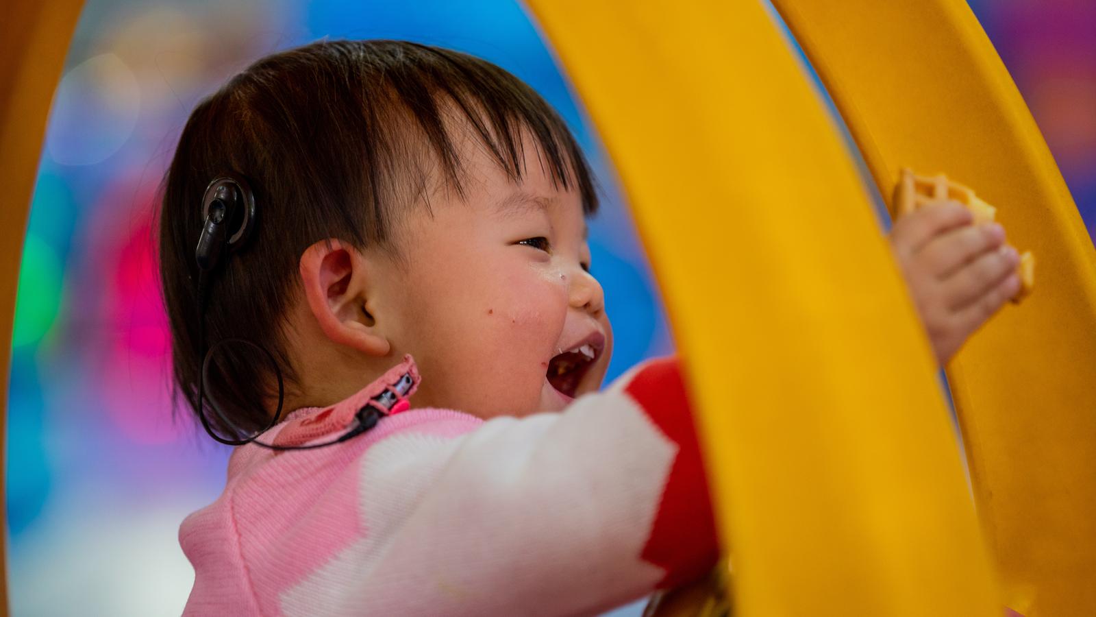 A young girl with a Cochlear implant draws with crayons