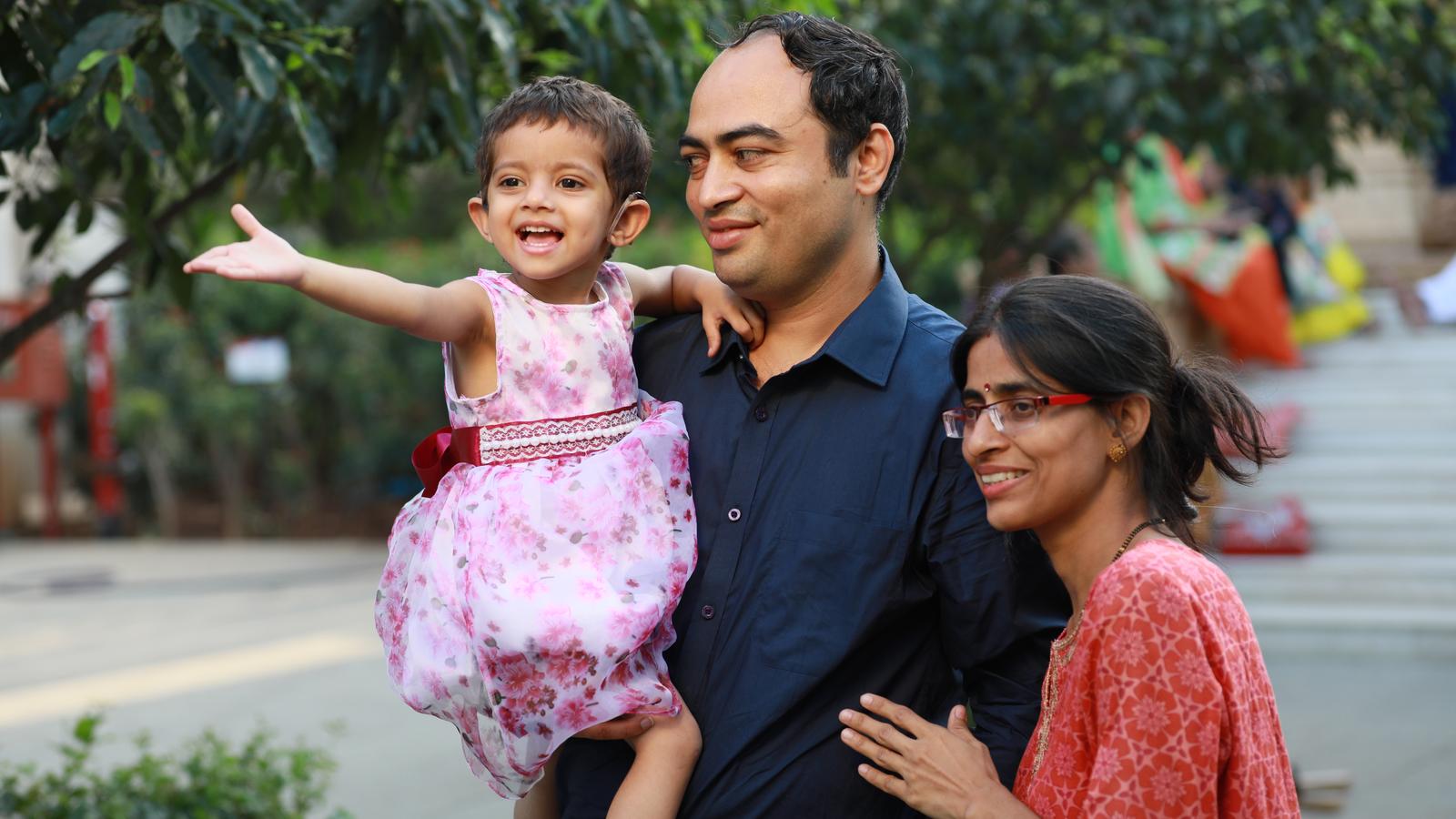 A girl wearing an implant is carried by her father