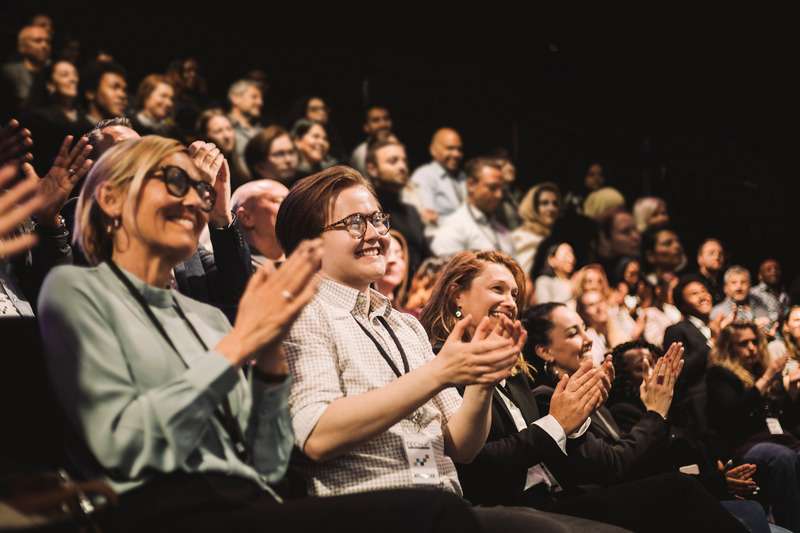 Personnes en train d’applaudir dans une salle de conférence.