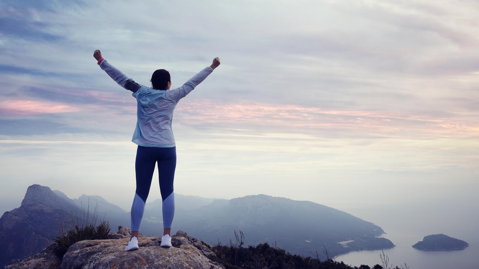 A woman stretching her arms and enjoying the sunrise