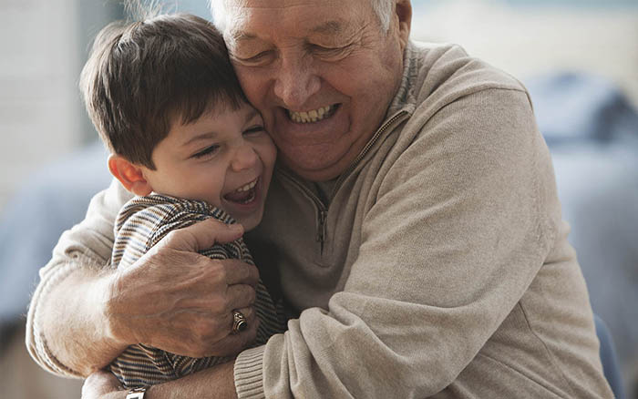 Cochlear implant kullanıcısı olan büyükbaba erkek torununa sarılmaktadır