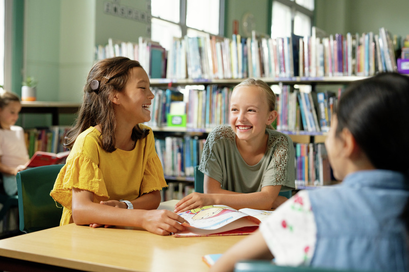 Three girls at school laughing with each other