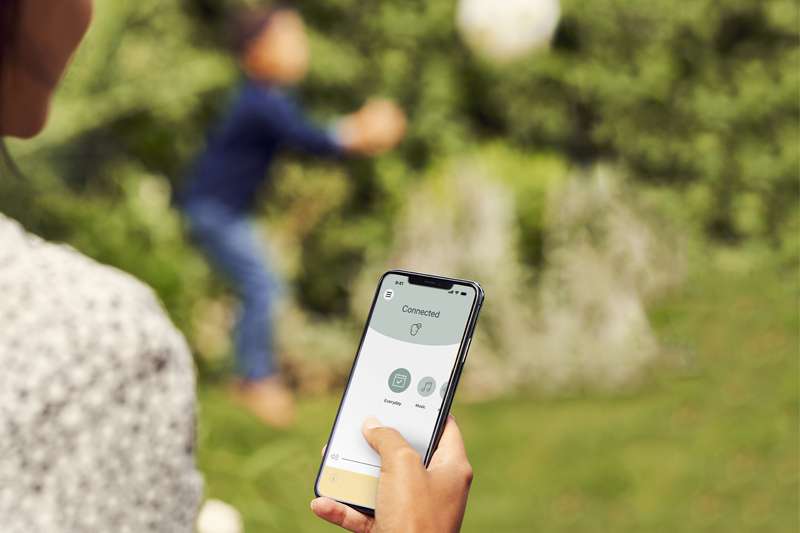 Personne consultant l’application Baha Smart sur un téléphone. En arrière-plan se trouve un jeune porteur d’un Baha Smart.
