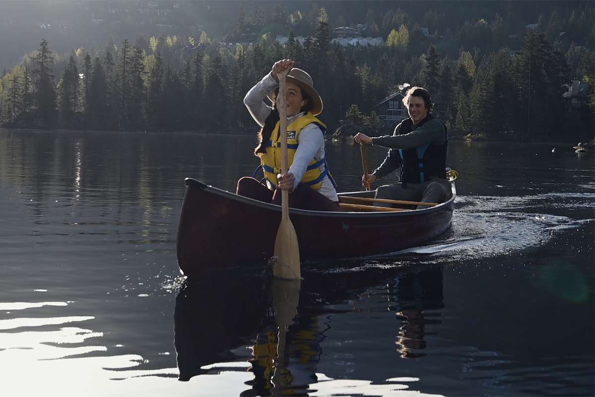 Une jeune femme et un homme faisant du canoë dans un lac.