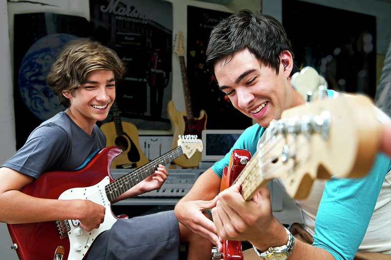 Two teenage males play electric guitar together