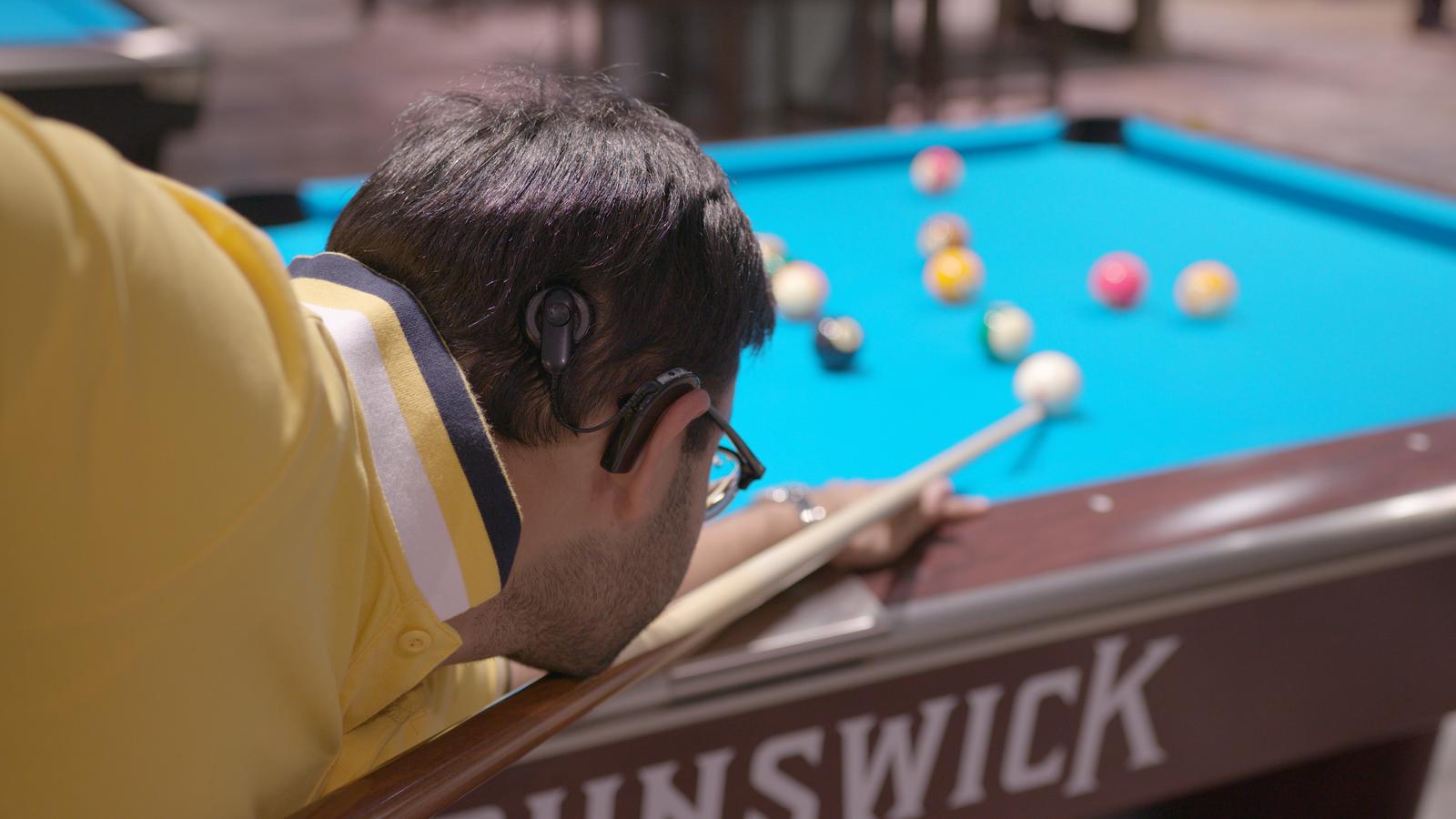 Người đàn ông đeo dùng thiết bị cấy ghép thính giác chơi snooker