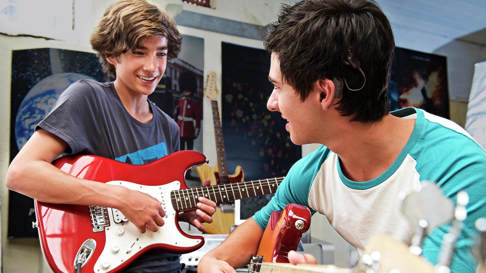 Cochlear recipient Christopher plays guitar with a friend