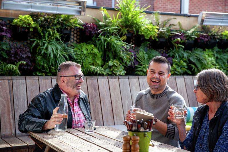 Three people sitting outside laughing and chatting