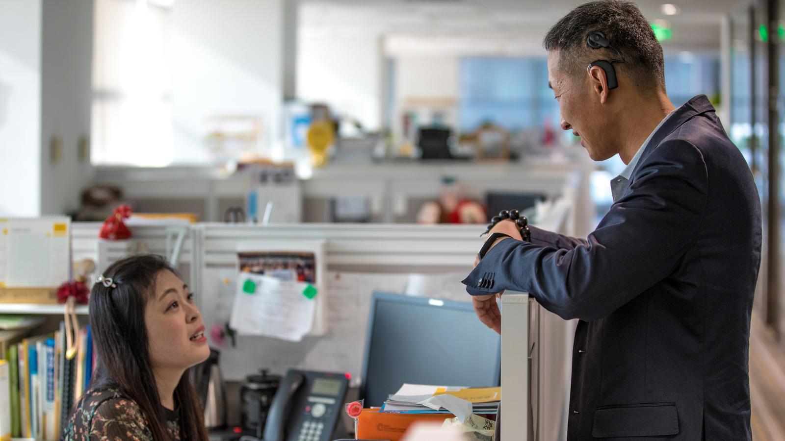 Kenneth laughs with coworkers as he wears his cochlear implants
