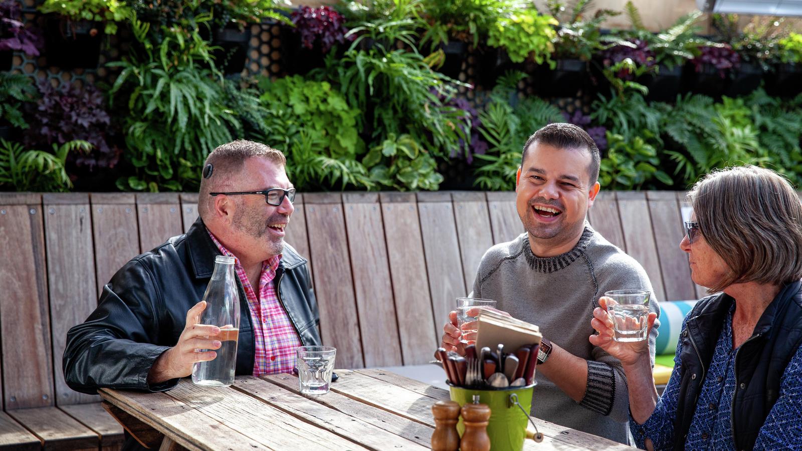 Three people sitting outside laughing and chatting