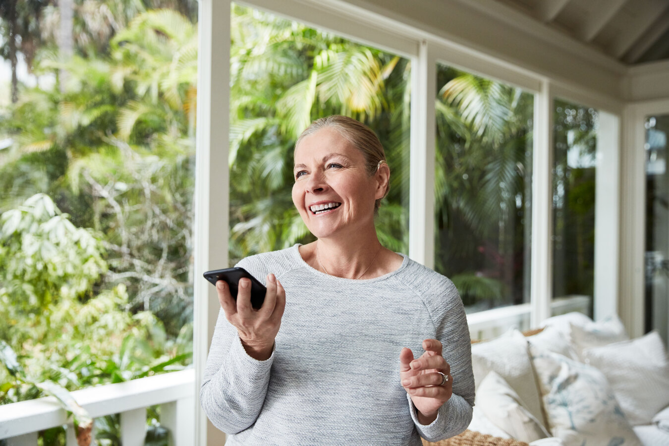 A woman wearing a Cochlear implant speaks on a smartphone