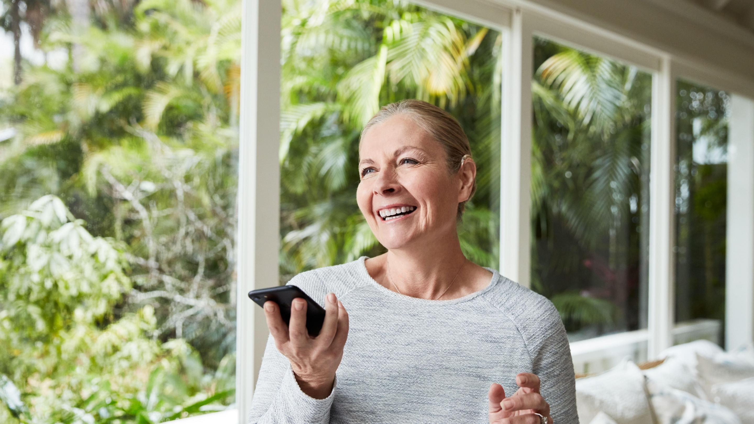 Kvinna med cochleaimplantat pratar i en smartphone