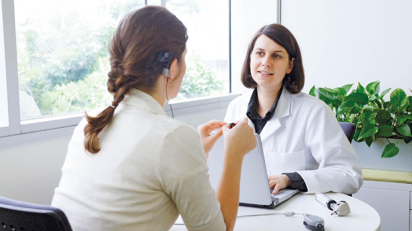 An audiologist conducts a hearing test with a patient