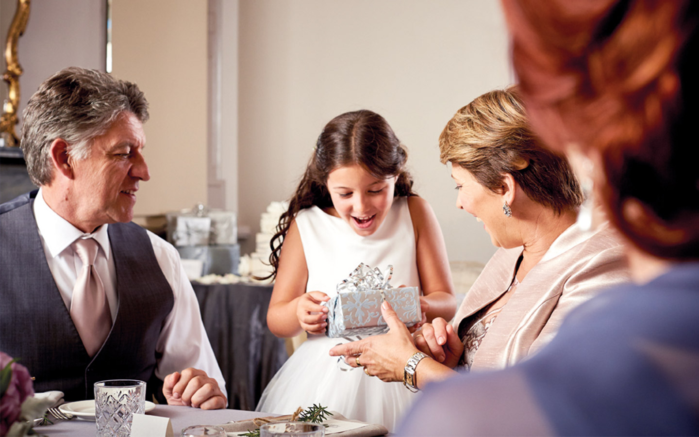 A girl holds a gift as her family watches on