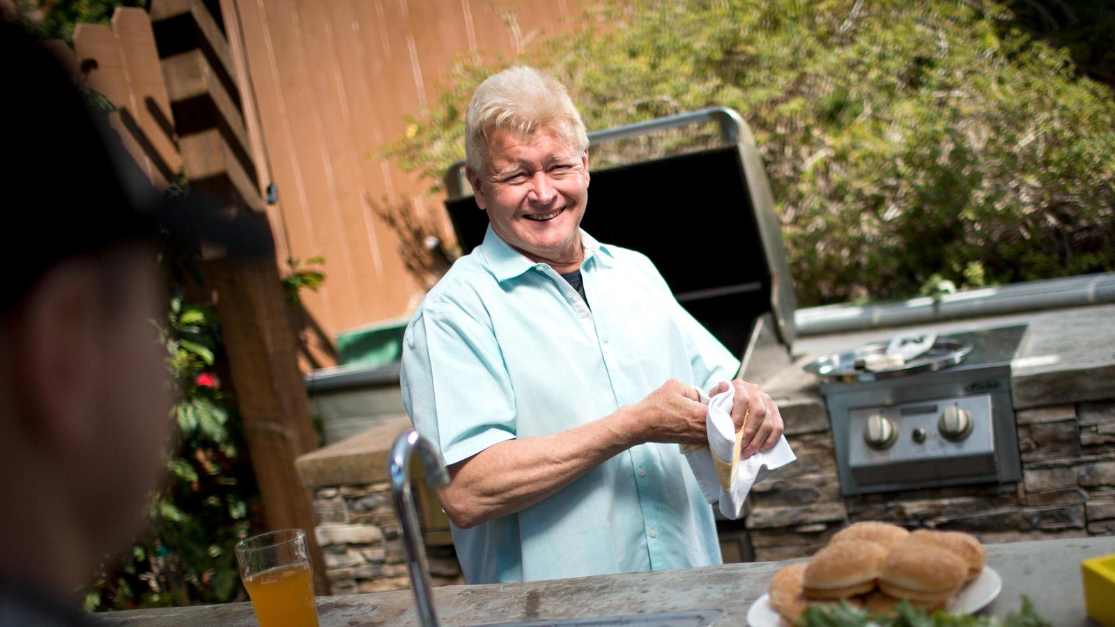 Un homme sourit à la caméra lors d’un barbecue